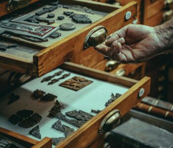 old artisan showing vintage and antique artifacts in wooden drawers