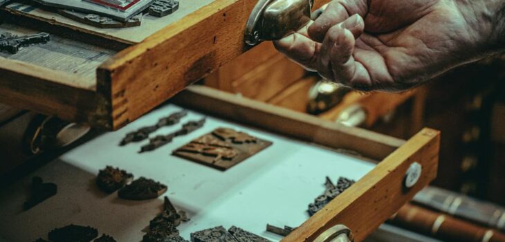 old artisan showing vintage and antique artifacts in wooden drawers