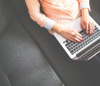 person sitting on gray sofa while using macbook