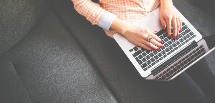 person sitting on gray sofa while using macbook