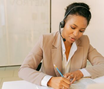 woman in beige blazer writing on white paper