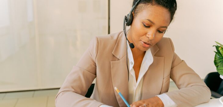 woman in beige blazer writing on white paper