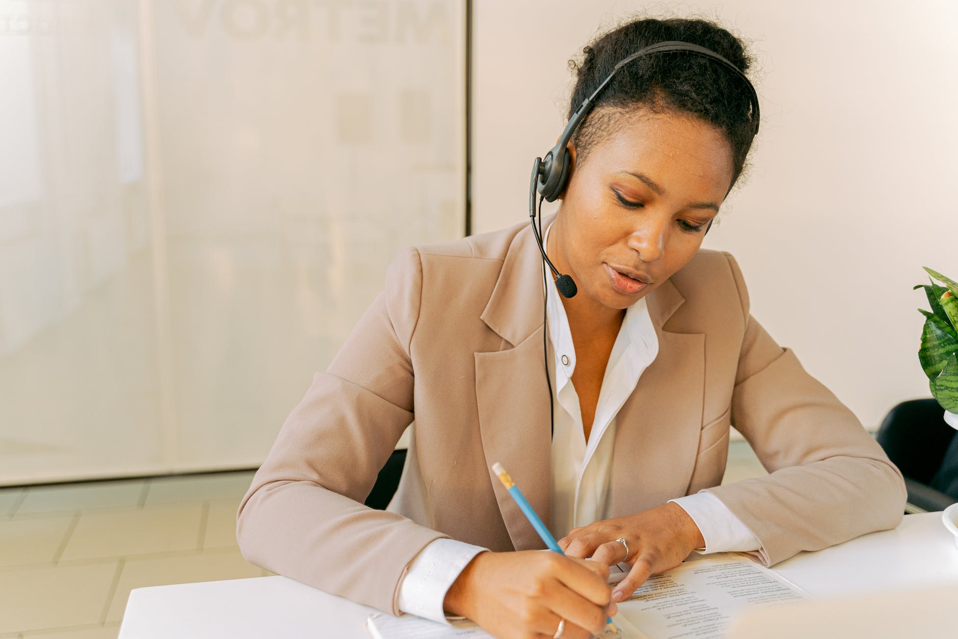 woman in beige blazer writing on white paper