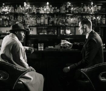 monochrome photo of men sitting in front of bar counter