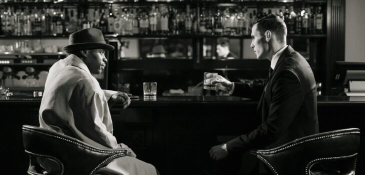 monochrome photo of men sitting in front of bar counter