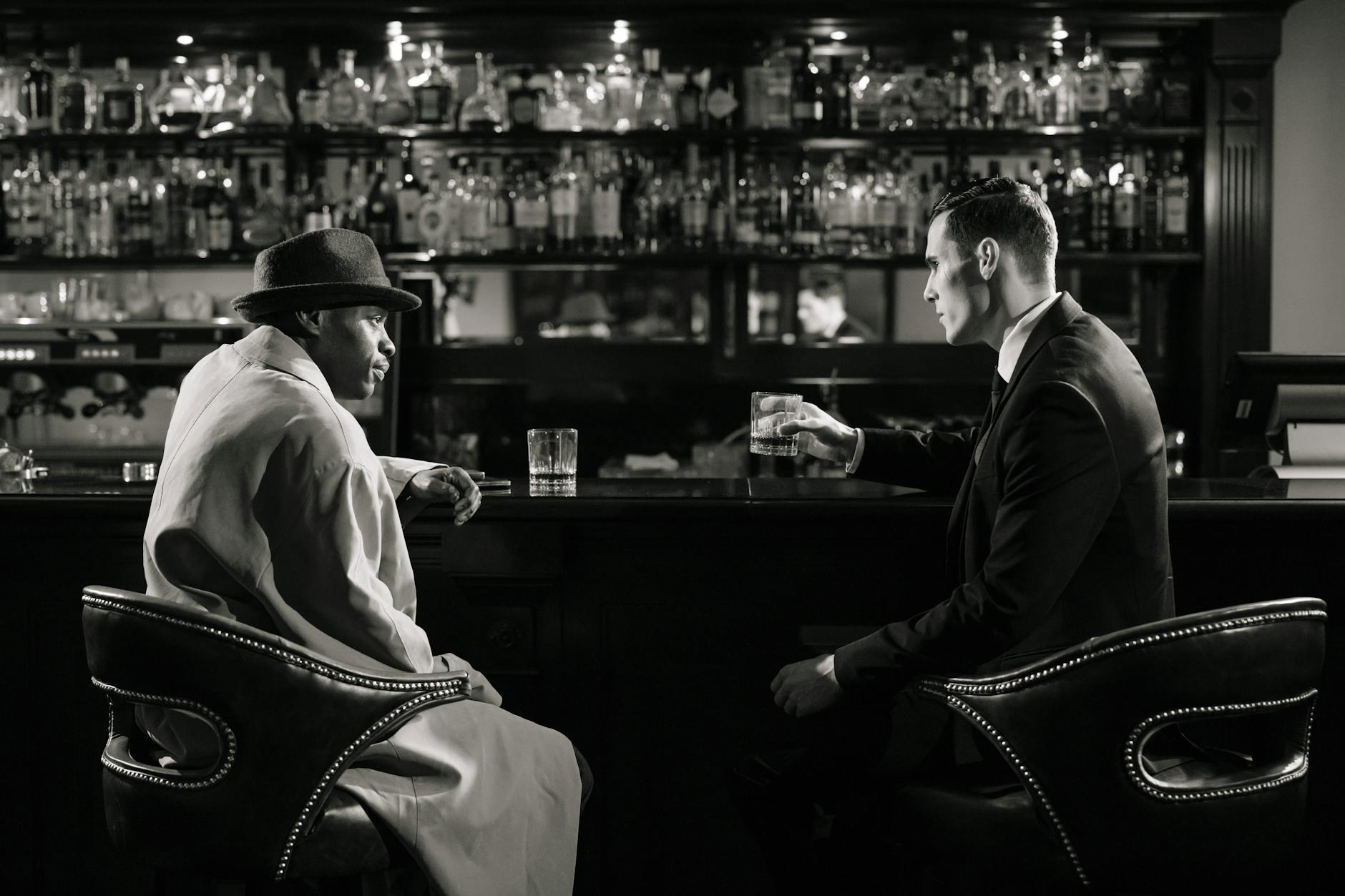 monochrome photo of men sitting in front of bar counter